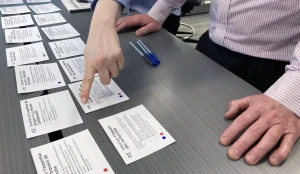 Deux chercheurs participants aux ateliers de co-design organisent des cartes sur un table pour prioriser des exemples de service. L'un des chercheurs pointe vers l'une des cartes.