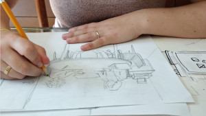 Une main dessine au crayon à mine une table avec deux personnes en train de discuter