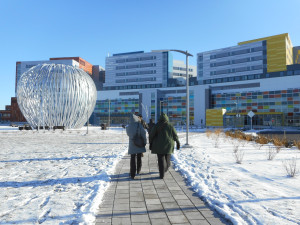 Photo du CUSM l'hiver avec deux personnes marchant en direction des bâtiments sur un chemin déneigé