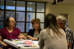 Des participantes qui expriment leurs points de vue à la facilitatrice, assis autour d'une table.